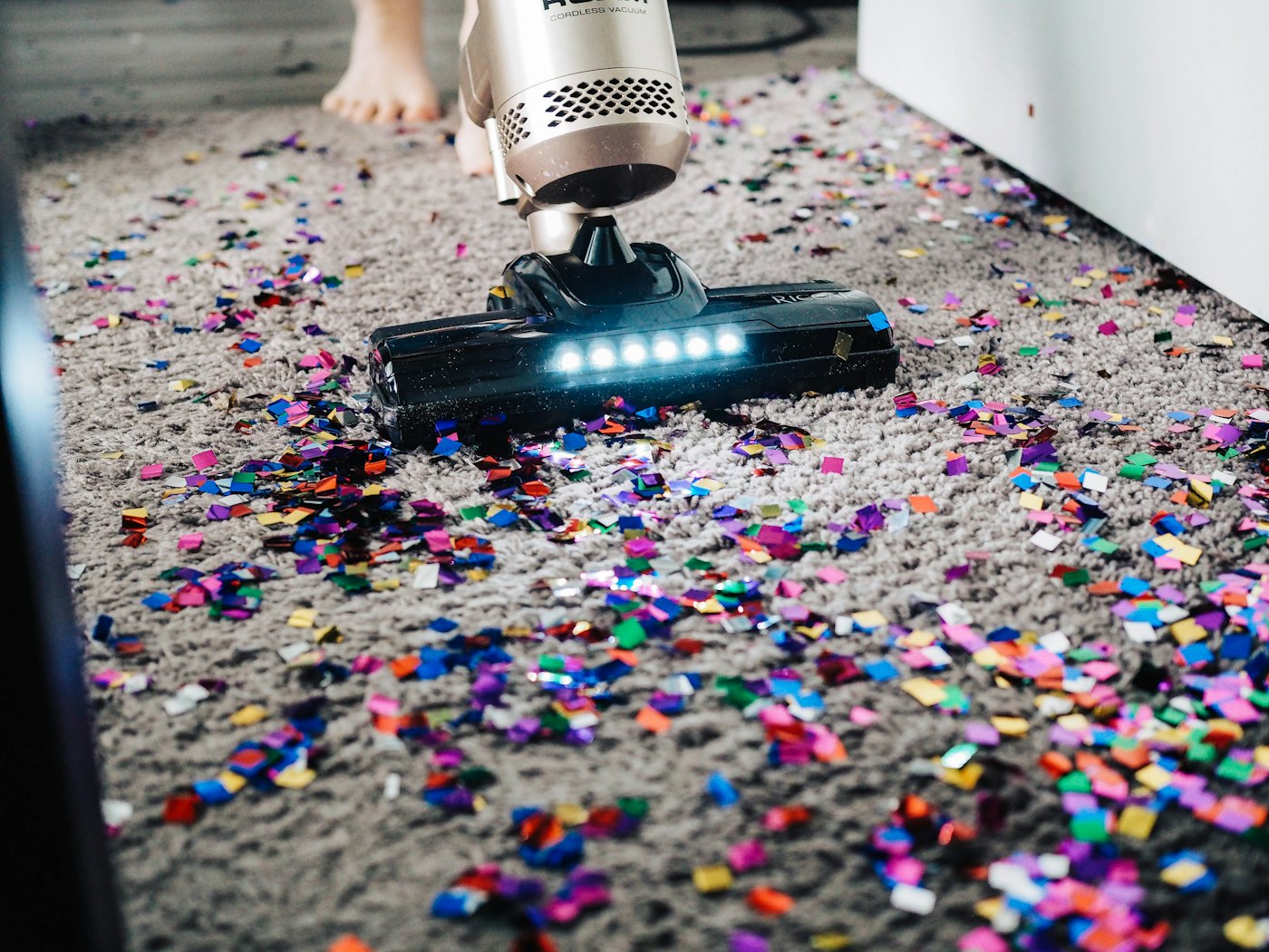 Aspiradora pasando sobre una alfombra gris con confeti, lavado de alfombras en Chile